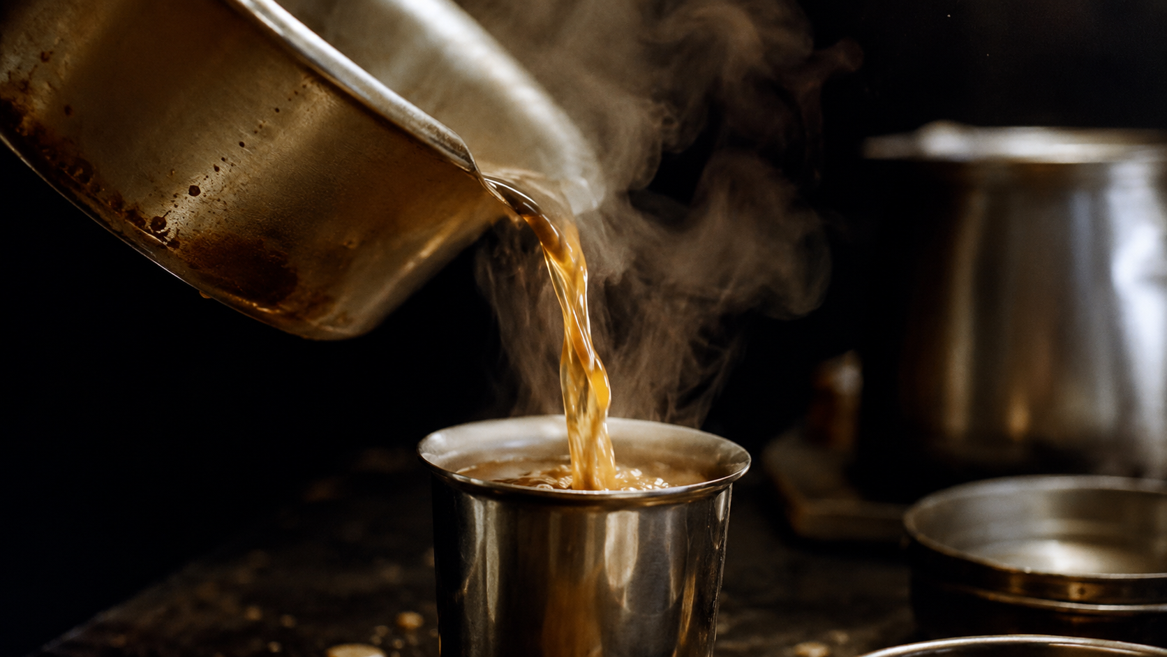Chai being poured from a pan into a steel cup